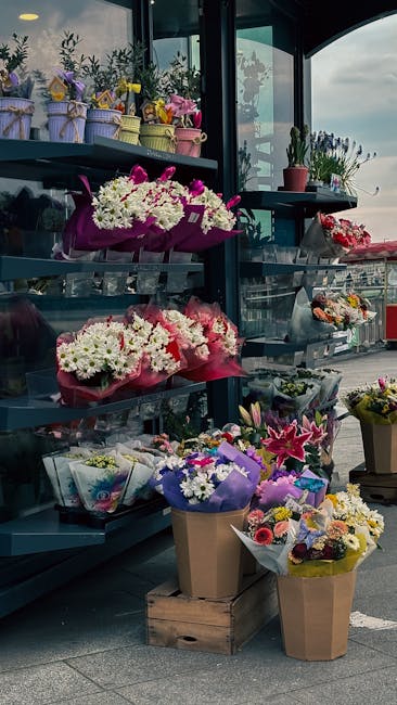 An indoor display of floral arrangements at flowerdeliveryfinchley.co.uk, featuring a variety of fresh flowers including white daisies, pink lilies, and purple irises, arranged in colorful wrapping pa